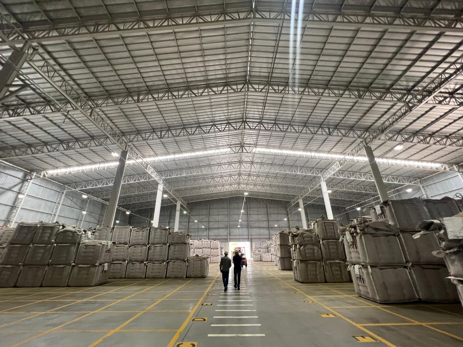 Interior de galpão industrial em operação, com pessoa em pé sob a estrutura