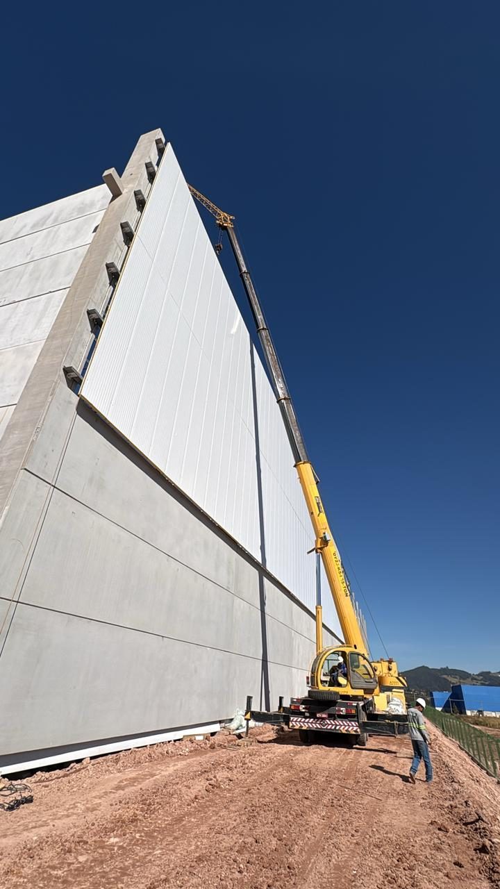 Guindaste içando placa de isopainel junto à parede da obra